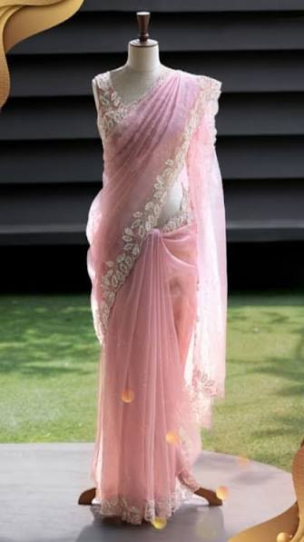 Delicate pink net saree with white floral embroidery on a mannequin